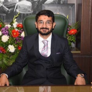 Senior advocate seated at a desk in a formal suit with a decorative floral backdrop at MP Legal Consultants.